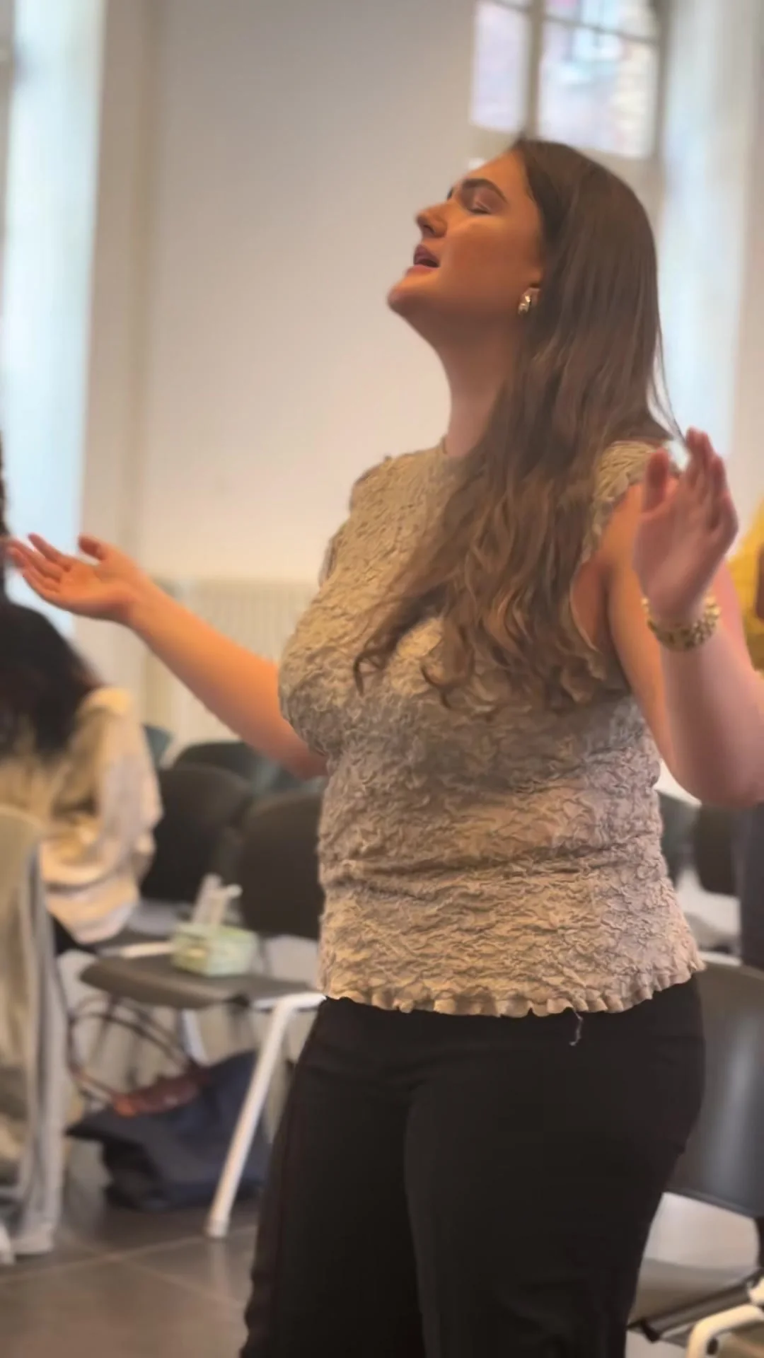 A young woman worshipping with her face lifted, eyes closed and palms open, at a Go Church service in Leuven.